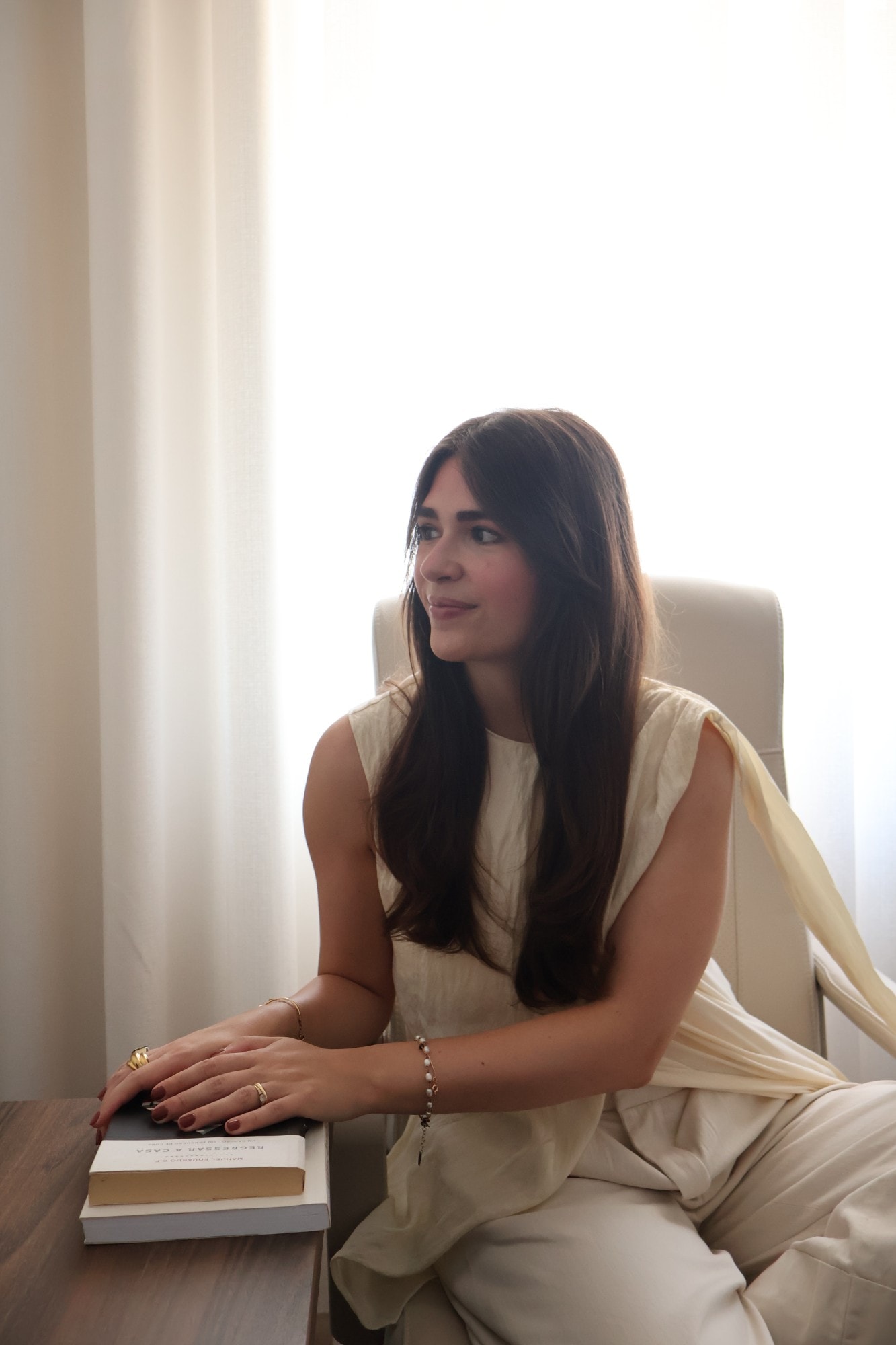 Stéphanie Jamet sentada num cadeirão junto à janela, com as mãos sobre dois livros