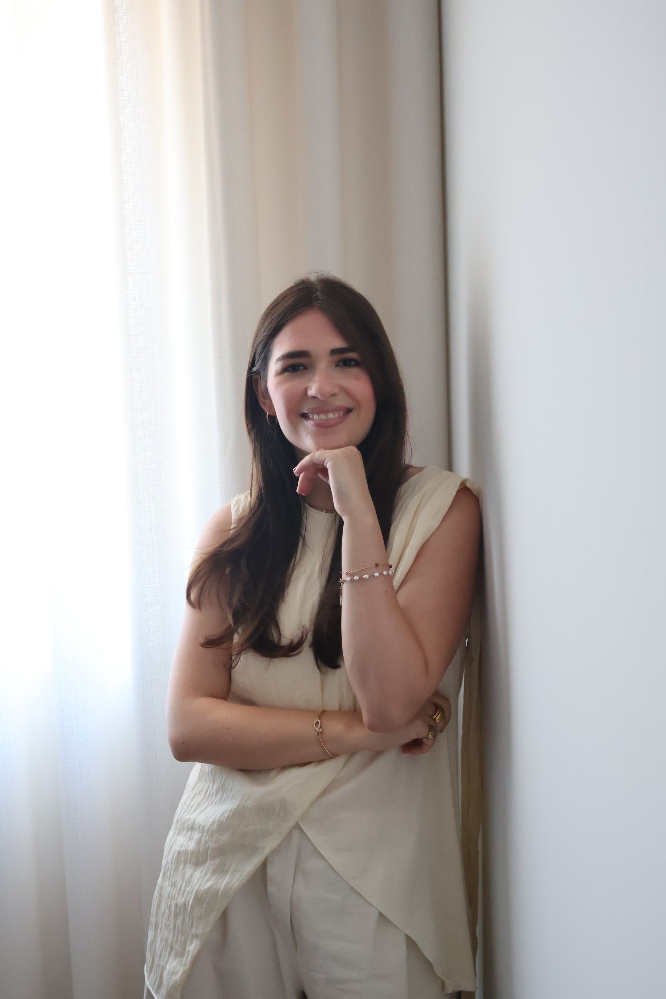 Stéphanie Jamet, psicóloga, a sorrir encostada a uma parede junto a uma cortina clara